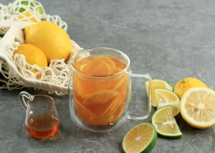 A glass mug of yuzu tea, filled with yuzu wedges, water, and honey.